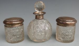 Three hallmarked silver topped cut glass dressing table pots and bottles comprising a globe shaped