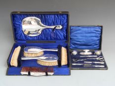 Cased hallmarked silver mounted dressing table set comprising hand mirror, four brushes and a