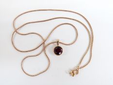 A 9ct gold necklace and pendant set with a round cut garnet, 3.3g