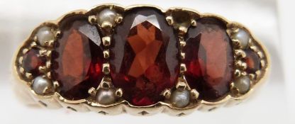 A 9ct gold ring set with five garnets and seed pearls, 3.4g, size S