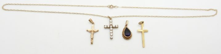 A 9ct gold cross, a 9ct gold pendant set with a pear cut amethyst, a 9ct gold crucifix and a 9ct