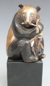 Bronze and gilt figure of a panda eating bamboo, initialled verso GK 91-5, height 15.5cm
