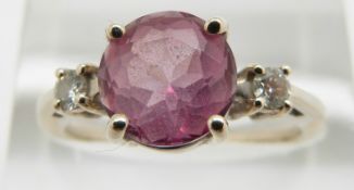 A 14k gold ring set with a pink sapphire flanked by a diamond to each shoulder, 3.2g, size O