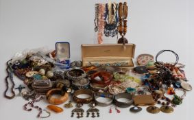 A collection of costume jewellery including amber brooch, compacts, bangles, agate necklace, vintage