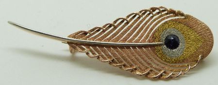 A tri-coloured gold brooch in the form of a peacock feather set with a sapphire, in original Jays of