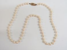 A single strand of cultured pearls with a gold clasp set with an emerald