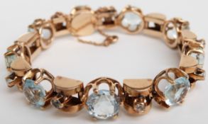 A yellow metal bracelet set with nine large and nine small round mixed cut aquamarines, total weight