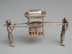 Chinese white metal novelty table ornament formed as a covered seat carried by two figures, marked