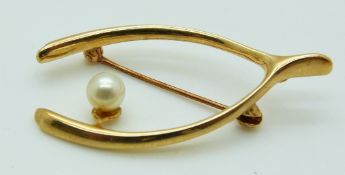 A 9ct gold brooch set with a pearl in a wishbone design, 4.1g
