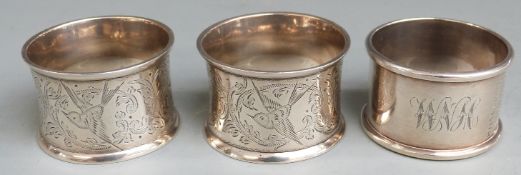 Three hallmarked silver napkin rings including a Victorian pair engraved with birds, London 1896