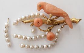 An 18ct gold brooch in the form of a parrot on a branch, the parrot of carved coral set with a