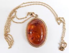 A 9ct gold pendant set with a pressed amber cabochon on a 9ct gold chain