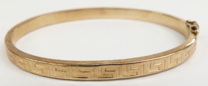 A yellow metal bangle with Greek key decoration, 7.43g (6.2 x 5cm)