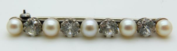 A silver brooch set with alternating pearls and white sapphires