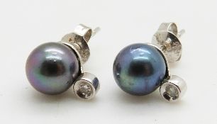 A pair of 14k white gold earrings set with a pearl and diamond to each