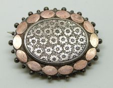 Victorian silver brooch with applied gold border and engraved foliate centre, verso glass