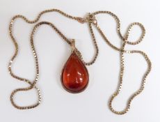 A yellow metal pendant marked 333 set with a pressed amber cabochon on a silver gilt chain