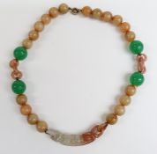 A jade necklace with elongated carved bead suspended from 20 spherical mutton fat beads, four larger