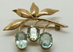A gold brooch/ pendant set with three oval aquamarines