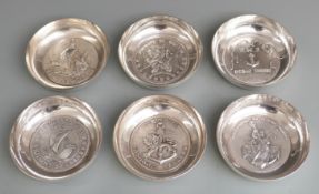 Set of six white metal shallow bowls or trays, each with shipping interest medallion to base, one