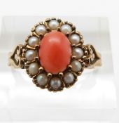 A yellow metal ring set with an oval coral cabochon surrounded by seed pearls, 3.3g, size P
