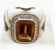 A yellow metal ring set with an emerald cut citrine surrounded by diamonds set with black and