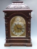 Victorian oak cased mantel/ boardroom clock ornately carved with masks and fruit, the silvered Roman