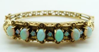 A 14k gold bangle set with six oval opal cabochons interspersed with round opal cabochons, 25.2g,
