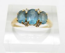 An 18ct gold ring set with three oval blue topaz and diamonds, 3.9g, size O