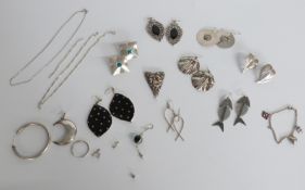 A collection of silver earrings including novelty fish and other examples and a charm bracelet