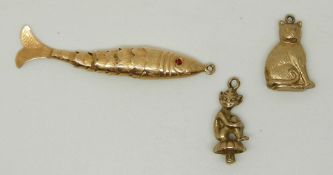 Two 9ct gold charms comprising a cat and a pixie (3.4g) and a yellow metal reticulated fish (2.3g)