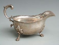 Edward VII hallmarked silver sauce boat with shaped edge, raised on paw feet and with scroll handle,