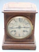 An oak cased two train mantel clock with silvered Roman dial, the two train movement striking on a