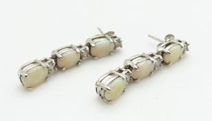 A pair of 14ct white gold earrings each set with three oval opal cabochons