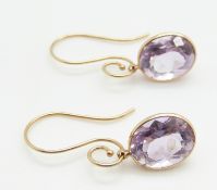 A pair of 14k gold earrings set with an oval cut amethyst to each