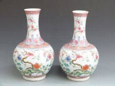 A pair of Chinese famille rose bulbous pedestal roulade vases with foliate, floral and bat
