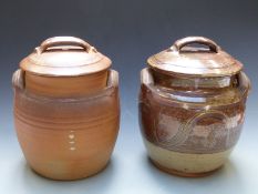 Two Winchcombe Pottery lidded twin handled crocks, one ribbed and the other with swirling