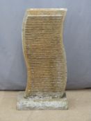 A carved granite water feature with rills to both sides, on base and with central hole for water,