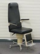 Optician's chair with folding arms and footrest and metal base raised on castors