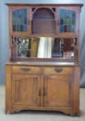 Arts and Crafts oak dresser, the top having two cupboards with leaded glass doors over a bevelled