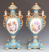 Pair of large porcelain pedestal twin handled covered vases with decorated cartouches of flowers and