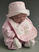 D P Creations Bountiful Baby Reborn doll with closed mouth, fixed blue eyes and pink outfit, 50cm
