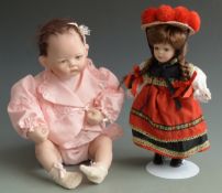 Two bisque dolls both with painted features, brown eyes and soft bodies, one on stand 31cm tall