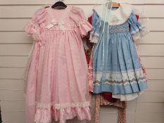 Twelve various girls' or dolls' dresses, many with floral and animal patterns and lace decoration.