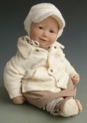 Vinyl doll with open mouth, fixed brown eyes and brown and cream outfit, marked to the back of the
