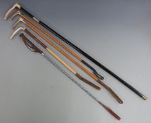Four riding crops, two with silver mounts and a walking stick