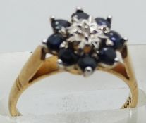 A 9ct gold ring set with a diamond surrounded by sapphires, 3.0g, size M