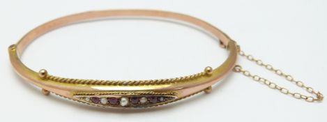 Edwardian 9ct rose gold bangle with rubies and seed pearls, 4.4g