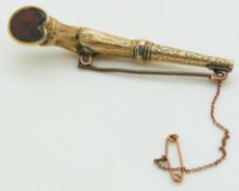 A yellow metal brooch/ seal in the form of a horse's hoof, set with a foiled garnet, 6cm long