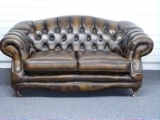 Chesterfield club style sofa finished in chestnut brown / tan leather with turned legs and brass cup